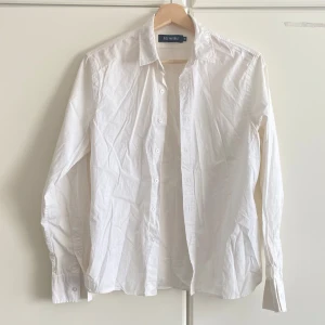Vit skjorta från Size & Needle - Klassisk vit skjorta från Size & Needle med lång ärm och knappar framtill. Skjortan har en snygg passform och är tillverkad i bomull, perfekt för en clean och stilren look. Enkel att matcha med jeans eller kostymbyxor.