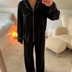 Lyxigt pyjamas set  - Säljer ett par svarta pyjamasbyxor med vit piping längs benslut. Byxorna har en loose passform och resår i midjan för extra komfort. Perfekta för chill dagar hemma eller mysiga kvällar. Materialet känns mjukt mot huden. Säljer även överdelen i detta inlägg