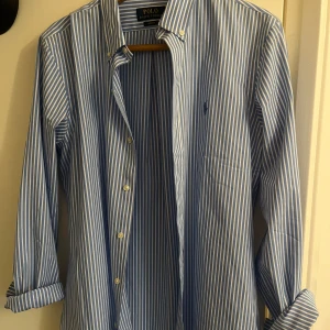 Blåvit randig skjorta Polo Ralph Lauren - Snygg blå och vit randig skjorta från Polo Ralph Lauren i slim fit-modell.  Helt sprillans ny då jag säljer den för att den var för stor. 