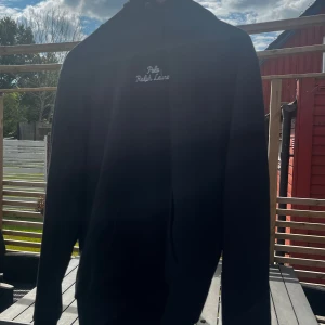 Svart hoodie från Polo Ralph Lauren - 🖤✨ Säljer en svart hoodie från Polo Ralph Lauren – klassisk & tidlös modell. 🔥 Perfekt för chill dagar men lika snygg till vardags.  👕 Detaljer: Huva, känguruficka & broderad logga på bröst & ärm. 🌿 Material: Mjuk bomull för bästa komfort.  📏 Storlek: M 💸 Nypris: 2200 kr – kvitto finns!  ✅ En hoodie som kombinerar stil, komfort & premiumkänsla – i toppskick & redo för ny ägare!