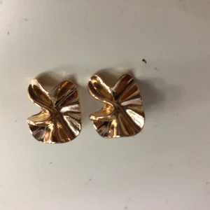 Guldiga  örhängen - Säljer ett par snygga örhängen i guld med vågig form. 
