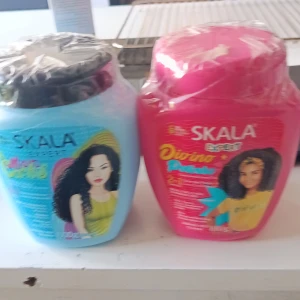 Skala Expert hårmask duo - Två stora burkar Skala Expert hårmask, en i blå och en i rosa förpackning. Båda är designade för lockigt hår och har illustrationer av tjejer med stora lockar på framsidan. Perfekt för dig som vill ge ditt hår extra fukt och näring. Plastförpackning med skruvlock.