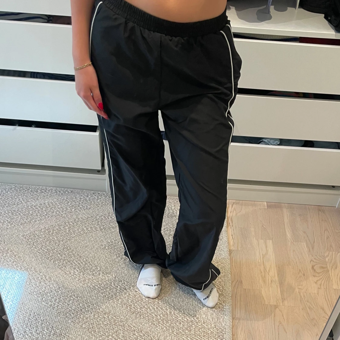 Svarta mjukisbyxor i glansigt material med vita detaljer