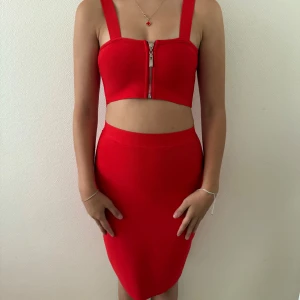 Röd tight set med hög midja - Snygg röd set med tight passform och hög midja. Kjolen är knälång och har en enkel, stilren design utan mönster eller detaljer. Perfekt för dig som gillar färgstarka plagg och vill sticka ut lite extra.
