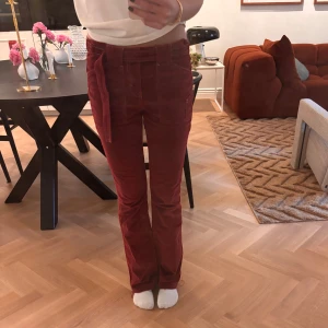 Röda manchesterbyxor med bootcut - Snygga röda manchesterbyxor med bootcut och låg midja. Byxorna har stora fickor fram, bakfickor med knapp och ett matchande bälte i midjan. Pris går att diskuteras. 