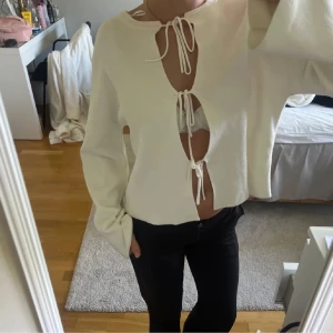 Vit kofta med snörning framtill - Superfin vit kofta med tre snörningar framtill som ger en öppen look. Långärmad och i mjukt stickat material. Perfekt för dig som gillar trendiga detaljer och vill sticka ut lite extra. Snygg att styla med både jeans och kjol.