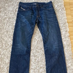 Diesel Larkee mörkblå jeans - Säljer ett par snygga Diesel Larkee jeans i mörkblå tvätt. Klassisk femficksmodell med raka ben och coola detaljer på bakfickorna. Jeansen har kontrastsömmar och är tillverkade i slitstarkt bomullsjeansmaterial. Perfekta för dig som gillar en tidlös och stilren look.