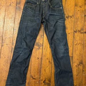 Mörkblå jeans Rag Freestyle RA-34 - Snygga mörkblå jeans från Rag Freestyle, modell RA-34. Klassisk femficksdesign med kontrasterande gula sömmar och unika bakfickor. Jeansen är raka i modellen och tillverkade i slitstarkt bomullsjeans. Perfekta för dig som gillar en clean och stilren look.