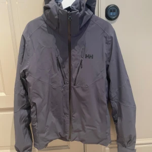 Helly Hansen skidjacka/outdoor jacka - Jackan har en sportig look, är tillverkad i syntetmaterial och har regular fit. Perfekt för blåsiga dagar och outdoor-aktiviteter.