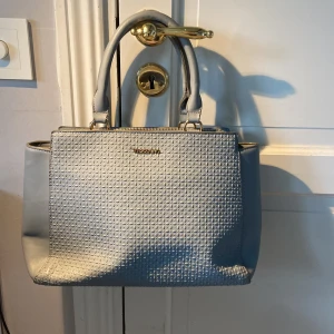 Ljusblå handväska från Vezzano - Ljusblå handväska från Vezzano med  guldfärgade detaljer. 