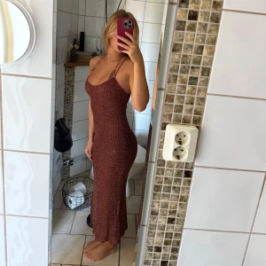 Glittrig vinröd klänning  - Supersnygg vinröd långklänning med glittriga detaljer i guld och smala axelband som går i ett kors i ryggen. Klänningen är figurnära och har en vågig struktur i tyget. Materialet är tunt stickat & är perfekt att ha över en bikini, så som jag har på bilderna🌊🐚storlek saknas men skulle tro att det är en xs-s