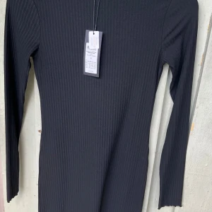 Svart ribbad långärmad klänning - Säljer en svart ribbad klänning från ONLY i storlek S. Klänningen har lång ärm och en kroppsnära passform med snygg ribbad struktur. Perfekt för dig som gillar stilrena och enkla plagg med lite edge.