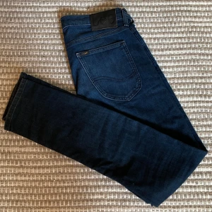 Mörkblå jeans Lee Luke - Snygga mörkblå jeans från Lee. Modellen Luke är slim fit. Jeansen är gjorda i mjuk bomullsblandning med lite stretch för extra komfort. Jag säljer nu flera Luke i samma storlek men olika färger!