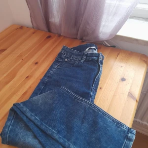 Blå jeans från Mywear Young, stl 152 - Snygga blå jeans från Mywear Young i klassisk femficksmodell. Jeansen har normal passform, raka ben och resår i midjan för extra komfort. Materialet är tåligt denim och färgen är mellanblå med lätt slitning på låren. Perfekta till vardags för en avslappnad look.