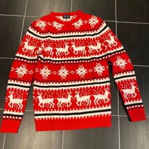 Röd jultröja med renar från BoohooMAN - Snygg röd stickad jultröja från BoohooMAN med vita och svarta detaljer. Tröjan har klassiskt julmönster med renar och snöflingor, rund hals och långa ärmar. Perfekt för att maxa julkänslan med stil! Använt 1 gång 