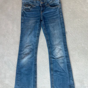 Blå bootcut jeans från Gina Tricot - Snygga blå jeans från Gina Tricot i storlek 140. Modellen har bootcut-ben, klassiska fickor fram och bak med coola detaljer och kontrastsömmar. Jeansen är i mjukt denimtyg och har en riktigt skön passform. Perfekta till sneakers eller boots!