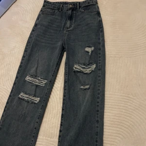 Blåa ripped jeans  - Snygg blå jeans och flera slitningar på benen för en trendig look. 