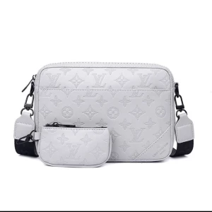 Vit axelväska från Louis Vuitton - Snygg vit axelväska från Louis Vuitton med klassiskt monogrammönster. Väskan har en bred axelrem och en liten matchande miniväska framtill. Tillverkad i skinn med präglad logga och detaljer i svart. Perfekt för dig som vill ha en clean och lyxig look.
