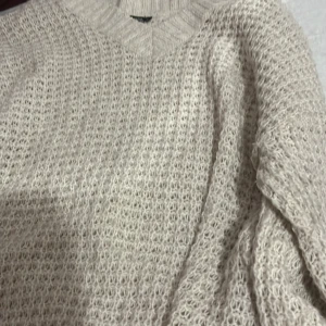 Beige stickad tröja från 157 - Mysig beige stickad tröja från 157 i storlek M. Tröjan har ett grovt stickat mönster och ribbad halsringning. Perfekt för lager-på-lager och chill dagar. Passar dig som gillar en enkel men ändå trendig look.