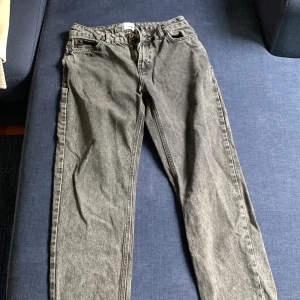 Grå jeans från Grant - Säljer ett par grå jeans från Grant med klassisk femficksdesign och raka ben. Jeansen har en snygg tvättad look och är tillverkade i bomull. Passar perfekt till en avslappnad stil och har en normal passform. Jeansen har litet hål längst ner men inget som märks.