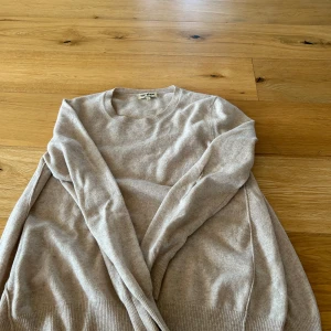 Beige kashmirtröja från Soft Goat - Supermjuk beige tröja i 100% kashmir från Soft Goat. Klassisk rund halsringning, ribbade muddar och långärmad modell. Perfekt för dig som gillar en clean och stilren look med lyxig känsla.