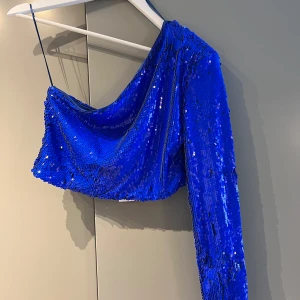 Blå paljett oneshoulder topp - Säljer en glittrig blå oneshoulder topp från Zara, täckt med paljetter. Aldrig använd. Storlek M.  Nypris 399 kr, mitt pris 200 kr. Köparen står för frakten🫶🏻