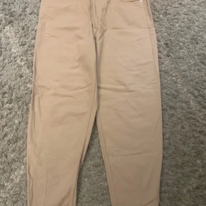 Beiga chinos med tapered fit - Snygga beiga chinos med tapered passform och klassisk design. Byxorna har fickor fram och bak samt dragkedjegylf. Perfekta för en clean och stilren look, lätta att matcha med både t-shirt och skjorta.