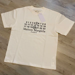 Maison Margiela vit t-shirt med tryck - Maison Margiela t-shirt i vit färg med ikoniskt svart tryck av siffror och logga på bröstet. Storlek S, helt ny med tags.