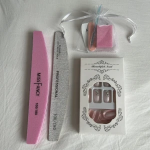 Nagelkit med lösnaglar och filar - Komplett nagelkit med rosa och silver nagelfilar, lösnaglar i ljusrosa med stenar, samt tillbehör som buffert, Alchol pad, Nagelbandsputare och en fil. Perfekt för att fixa snygga naglar hemma. Filarna har 100/180 grit och lösnaglarna har elegant design.