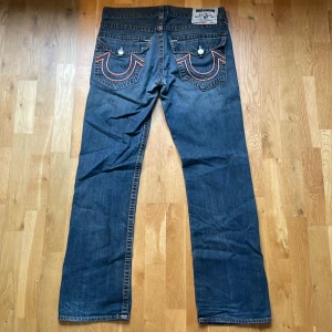 Blåa True Religion jeans  - Blåa jeans från True Religion med orangea sömmar i storlek 34! Skriv gärna för mer bilder på jeansen om de behövs🥰
