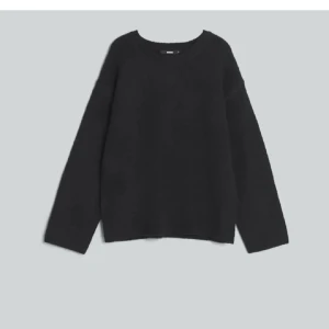 Svart stickad tröja med rund hals - En enkel svart stickad tröja med rund hals och långa ärmar. Perfekt för dig som gillar en clean och chill stil. Tröjan har en loose passform och är supermjuk, vilket gör den skön att bära under kyliga dagar.