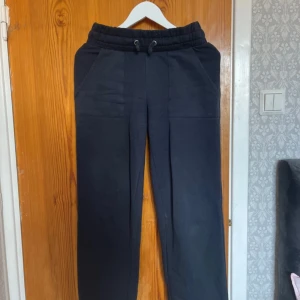 Svarta mjukisbyxor från 157 XS - Svarta mjukisbyxor från 157 i storlek XS. Byxorna har resår och snörning i midjan, raka ben och stora fickor både fram och bak. Perfekta för chill dagar eller när du vill vara extra bekväm.