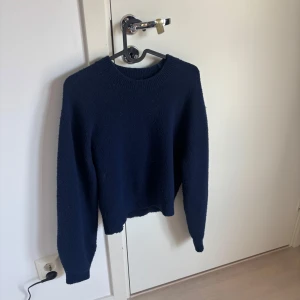 Mörkblå stickad tröja - Mysig mörkblå stickad tröja med rund halsringning och långa ärmar. Tröjan har en lite loose passform och ribbade muddar vid ärmslut och nederkant. Perfekt att slänga på sig när det är kyligt ute!