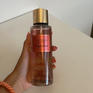 Victoria's Secret Temptation mist - Fräsch och fruktig body mist från Victoria's Secret i doften Temptation. Flaskan är transparent med rosa etikett och guldigt lock. Doften har inslag av äpple och ökenblomma. Rymmer 250 ml och är perfekt för dig som gillar söta och fruktiga toner.