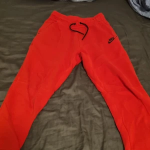 Röda mjukisbyxor från Nike L - Riktigt snygga röda mjukisbyxor från Nike med svart logga på låret. Byxorna har elastisk midja med svart snörning och muddar vid bensluten. Perfekta för chill eller träning. Mjukt material som känns skönt mot huden. Pris kan diskuteras. Skriv vid minsta fundering😊