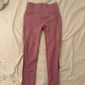 Rosa seamless leggings med hög midja - Säljer ett par rosa seamless leggings med hög midja och snygga mesh-detaljer längs sidorna. De är stretchiga och sitter tight, perfekta för träning eller chill. Materialet är mjukt och följsamt, vilket gör dem riktigt bekväma att ha på sig.