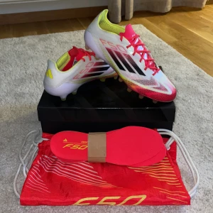 ADIDAS F50 ELITE AG PURE VICTORY - VIT/SVART/GUL - Snygga ADIDAS F50 ELITE AG PURE VICTORY - VIT/SVART/GUL. Skorna är använda i 10 minuter, så i princip som nya. Skorna har snörning och är tillverkade i lätt syntetmaterial för maxad speed på planen. Kommer med extra innersulor och röd F50-påse. Perfekta för dig som vill sticka ut på matchen. Skicka om du vill ha fler bilder eller har andra funderingar. Tveka inte på att höra av dig!     Mvh Axel 🤝 🔴🟡⚪️