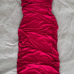 Röd omlottklänning från SHEIN - Säljer en snygg röd omlottklänning från SHEIN i storlek M. Klänningen har en tight passform med coola rynkade detaljer längs hela längden som ger en unik look. Materialet är mjukt och stretchigt, perfekt för dig som vill sticka ut.