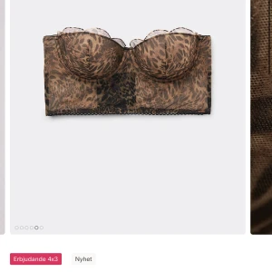 Leopardmönstrad bustier tubtopp - Snygg tubtopp i bustiermodell med leopardmönster i bruna och svarta toner. Toppen har vadderade kupor och transparent meshmaterial med dekorativ kant upptill. Perfekt för att skapa en trendig och djärv look.