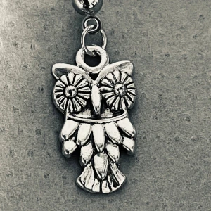 By prisförslag- 1 st Silvrigt örhänge med uggla - Unikt örhänge med en cool uggla som hänge i silverfärgad metall. Ugglan har detaljerade fjädrar och stora, blommiga ögon som verkligen sticker ut. Perfekt för dig som gillar djurmotiv och vill ha något annorlunda i smyckeslådan.