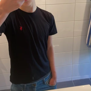 Ralph Lauren T-Shirt  - Svart Ralph Lauren T-shirt, helt ny, oanvänd och med prislappen kvar i storlek S! | Skick: 10 / 10 | Nypris : ~ 1000 | Vårt pris: 349 | Storlek: S