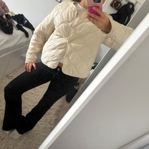 Beige quiltad pufferjacka - Säljer en beige quiltad pufferjacka med snygg vågig sömnad och tryckknappar framtill. Jackan har en boxig passform och är perfekt för dig som gillar en clean och trendig look. Långärmad och lätt vadderad för extra komfort. Osäker på storleken men jag brukar ha xs-s och den passar mig perfekt 