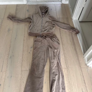 Beige sätt från Lindex - Säljer ett par beige mjukisbyxor från Lindex i mjuk velour med dragsko i midjan och två bakfickor. Byxorna har en loose passform och matchar perfekt med den tillhörande hoodien. Snyggt och bekvämt set för chill dagar.