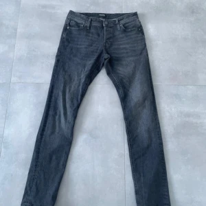 Slim fit svarta jeans Jack & Jones - Slim Glenn jeans från Jack & Jones i mörkgrå tvätt. Klassisk femficksmodell med smal passform och normal midja. Jeansen är tillverkade i stretchig bomullsdenim för en bekväm känsla och snygg look.