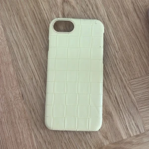 Ljusgul rutmönstrad mobilväska - Snygg ljusgul mobilväska med rutmönstrad struktur. Väskan har en stilren och enkel design som passar perfekt till din mobil. Materialet känns mjukt och ger ett modernt intryck.