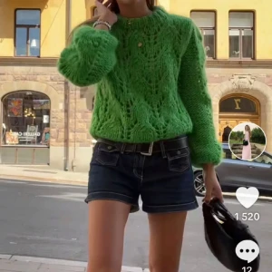 Grön stickad tröja med mönster - Säljer en cool grön stickad tröja med unikt hålmönster och fluffiga långärmar. Perfekt för dig som vill sticka ut med färg och struktur. Tröjan har en rund hals och är loose fit, vilket gör den både bekväm och trendig. Passar till jeans eller kjol för en snygg look. GANNI STORLEK S