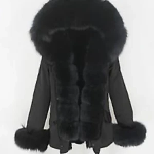 Svart parkajacka med fuskpäls - Säljer en svart parkajacka med stor fluffig fuskpäls runt huva, krage och ärmslut. Jackan har dragkedja och knappar framtill samt praktiska fickor. Perfekt för kalla dagar när du vill vara både varm och snygg, tyvärr är fluffet på armarna borta, pris går att diskutera 