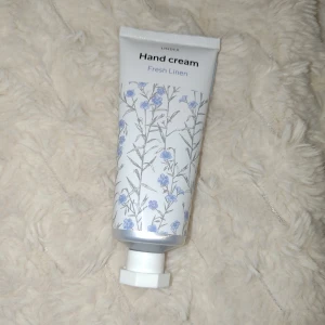 Handkräm - Handkräm med doft av Fresh Linen från Lindex i en vit tub med blå blommor och silverdetaljer. Tuben rymmer 50 ml och har en praktisk vit skruvkork. Innehåller bland annat sheasmör, sötmandelolja och aloe vera för mjuka händer. Helt ny!