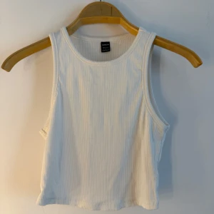 Vitt linne  - Vit, ribbad crop top med rund halsringning och breda axelband. Storlek S