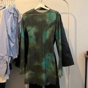 Grön och blå meshklänning med lång ärm - Säljer en cool meshklänning med lång ärm i gröna och blå toner. Klänningen är genomskinlig 